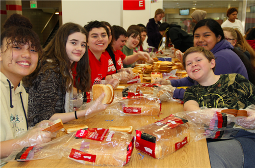 Ninth-grade students assemble sandwiches for homeless people in need. 